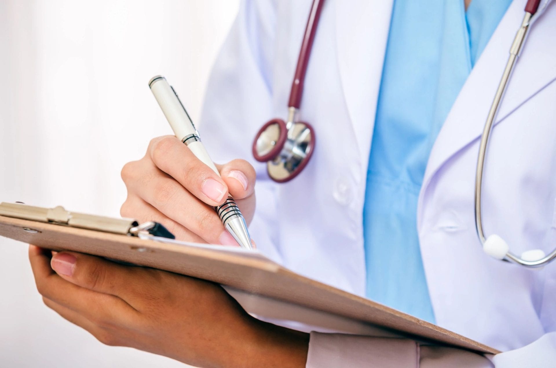 doctor signing a clipboard